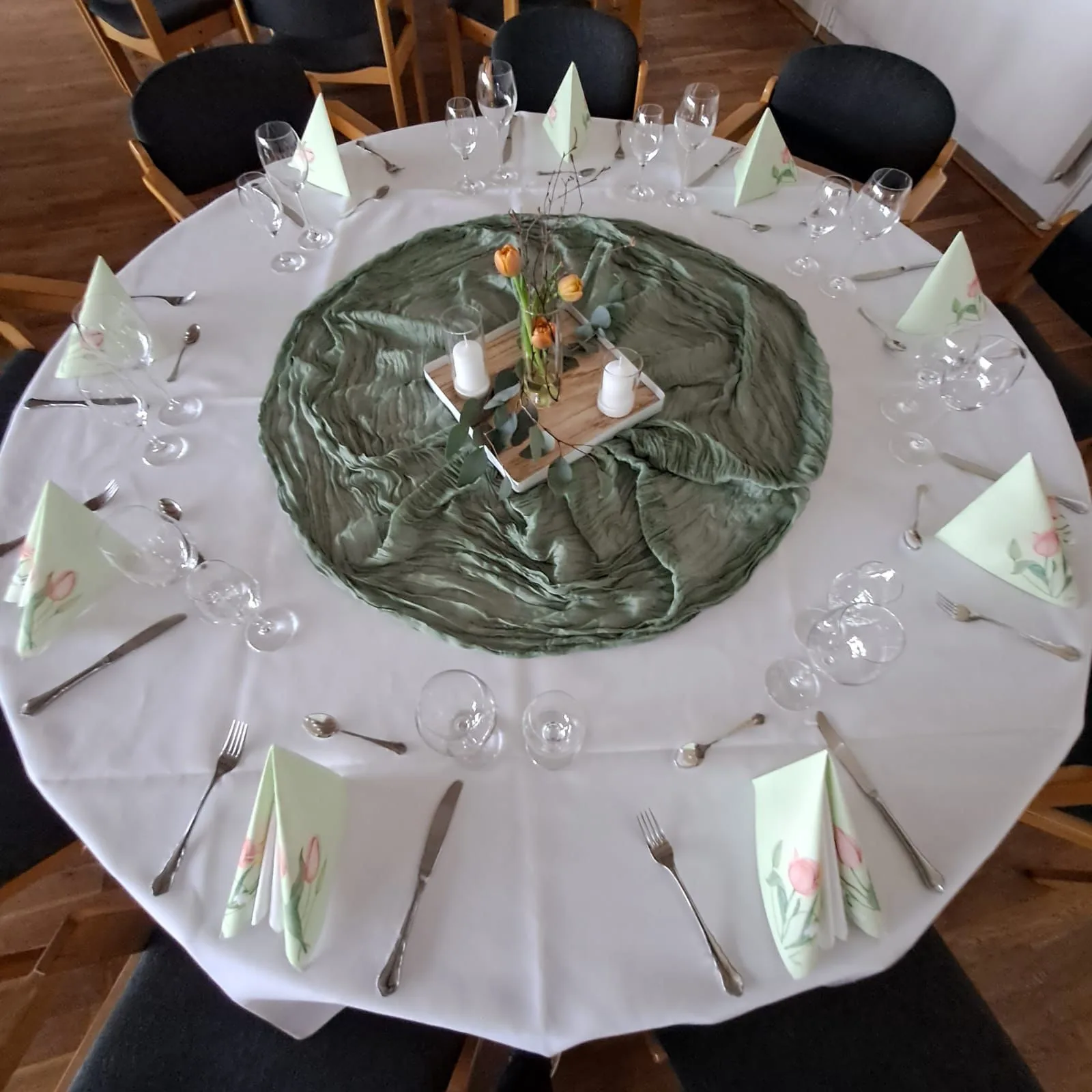 Runde Tafel von oben: salbeigrüner Läufer in der Mitte, Servietten mit Tulpenmuster, Kerzen und Gläser
