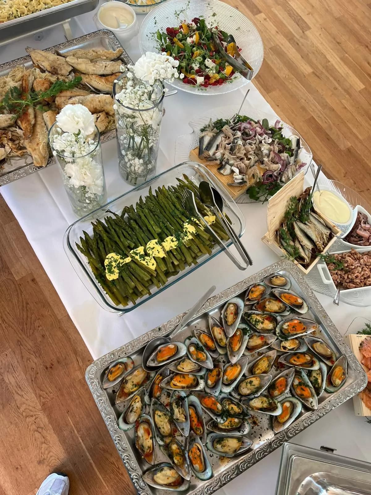 Buffet auf weißem Leinen: grüner Spargel, Miesmuscheln, Salate und Aufschnitt