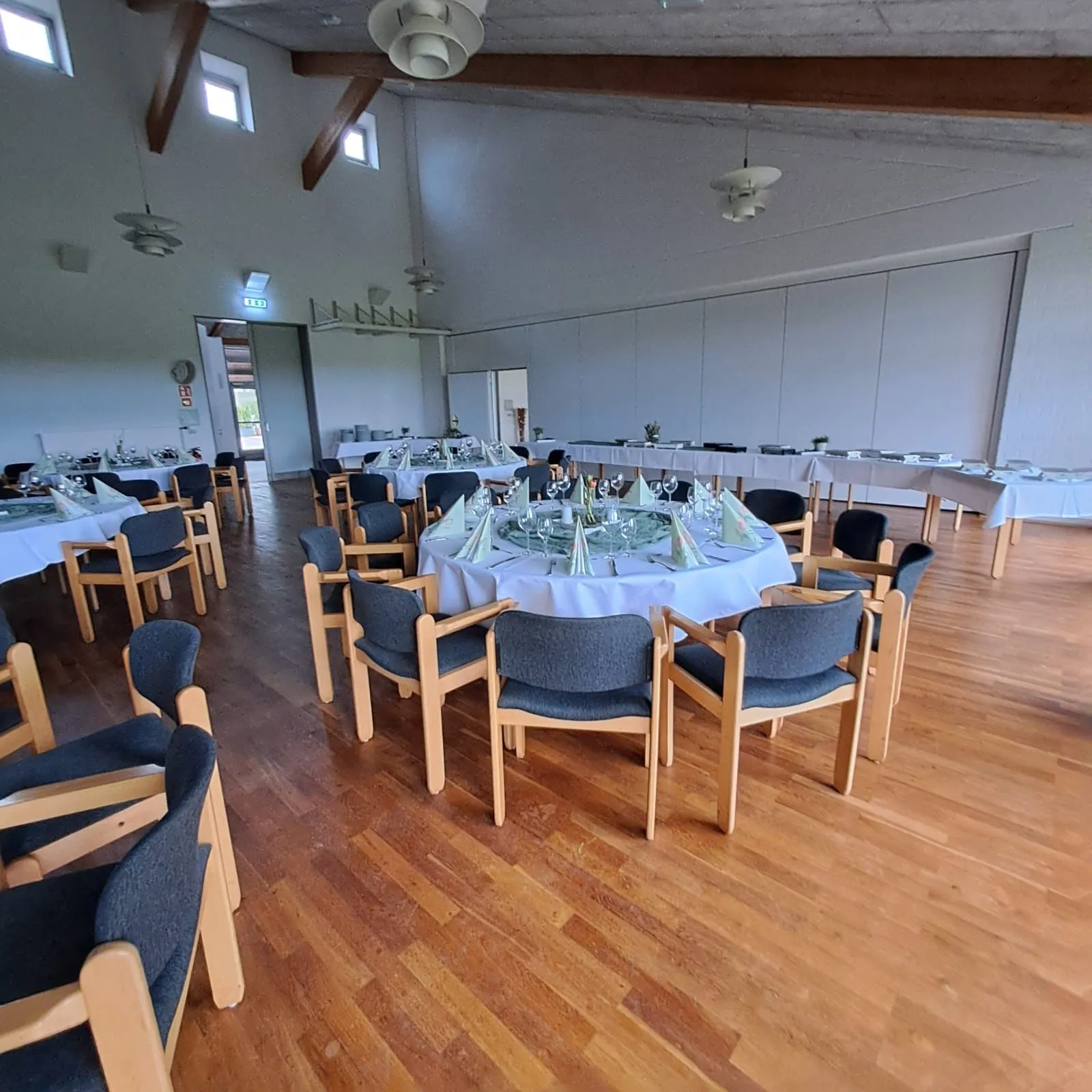Der Saal mit langen, gedeckten Tafeln entlang der Wände